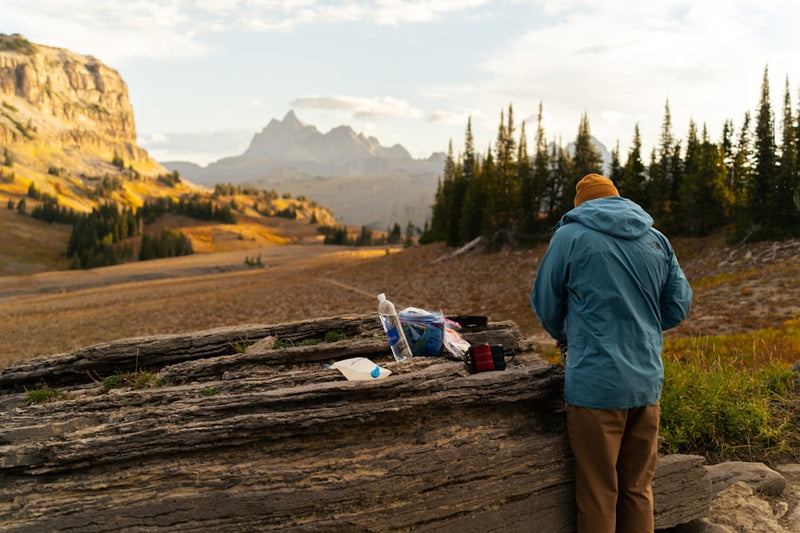 Hiker with backpack on rocky terrain at sunrise