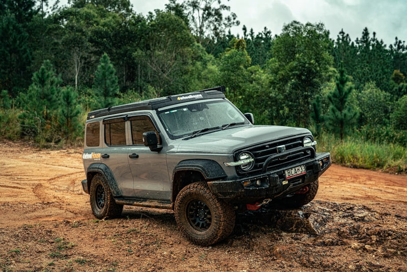 A silver off-road vehicle navigates a rocky trail.