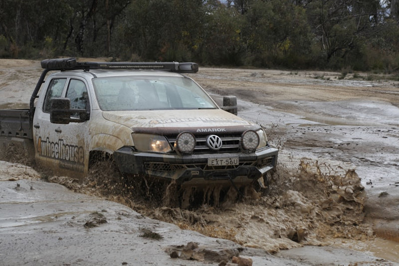 White pickup truck driving through mud and water
