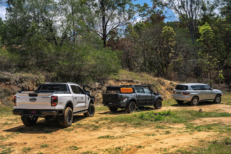 Three off-road vehicles parked on a dirt track.