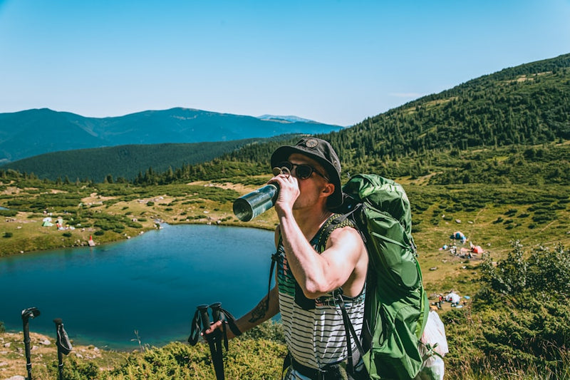 a man with a backpack drinking from a water bottle