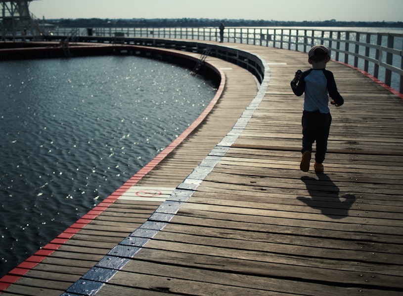 a person walking across a wooden bridge over a body of water