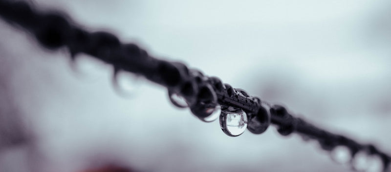 A black and white photo of raindrops on a wire