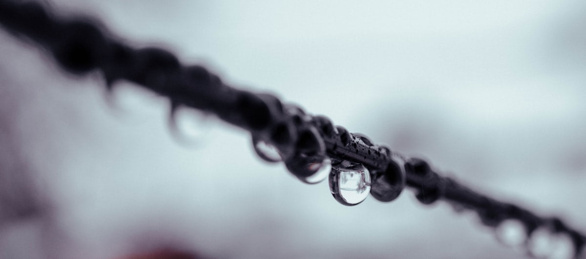 A black and white photo of raindrops on a wire