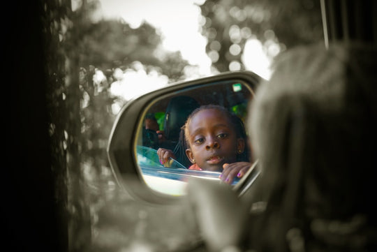 A child gazes in the side mirror.