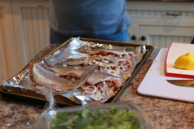 Raw fish prepared on a baking sheet with foil.