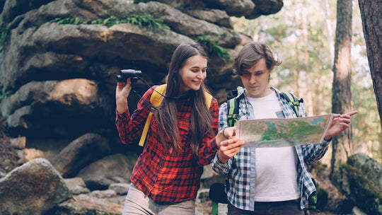 Couple looking at map while hiking in forest