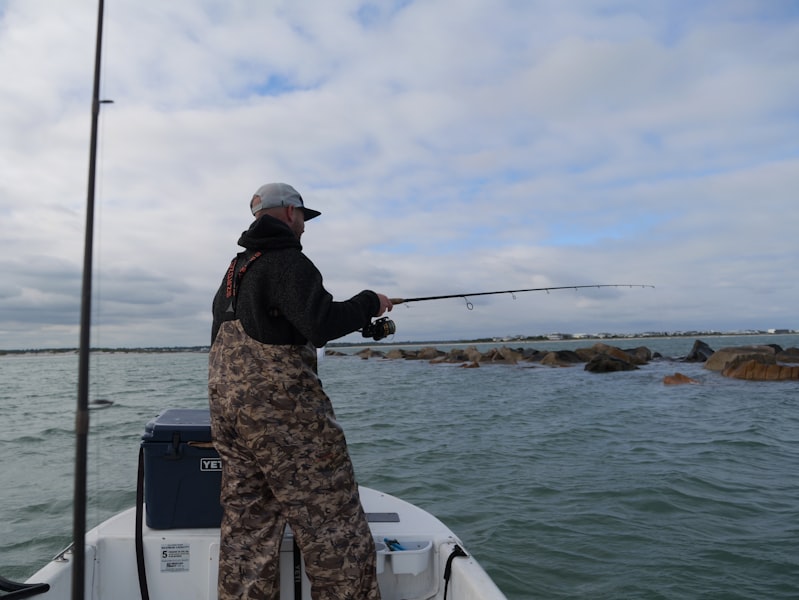 Man fishing from a boat near rocky shore