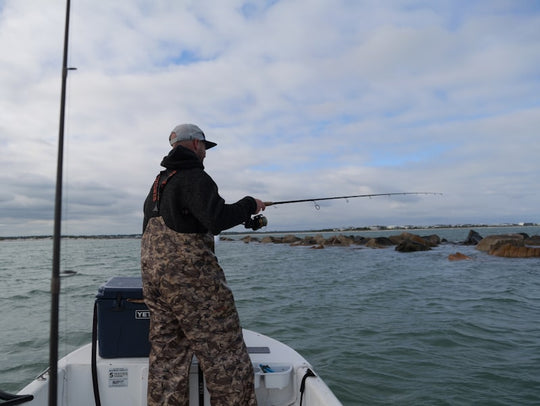 Man fishing from a boat near rocky shore