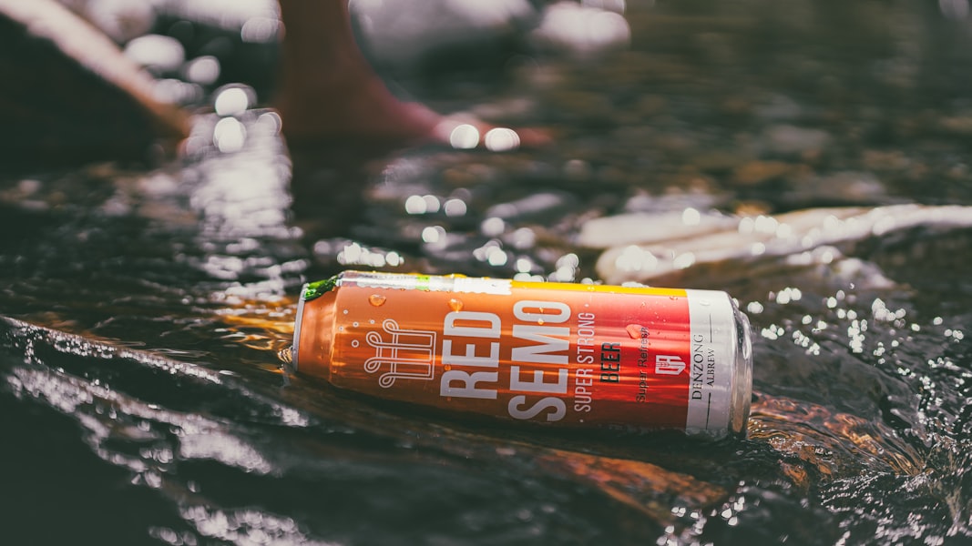 A can of red semo beer floats in a stream.