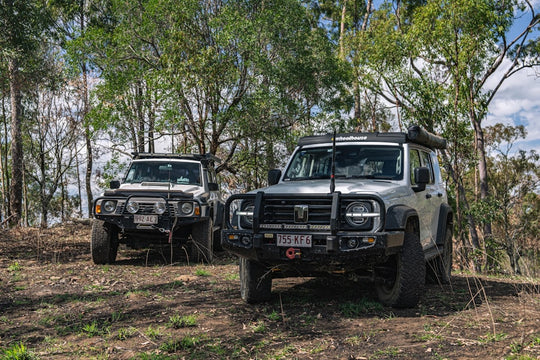 Two off-road vehicles parked in a wooded area.