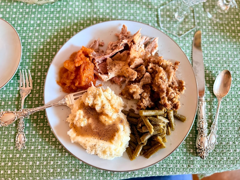 A plate of thanksgiving dinner with turkey and sides.