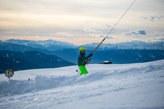 A skier in bright green pants holds ski lift pole