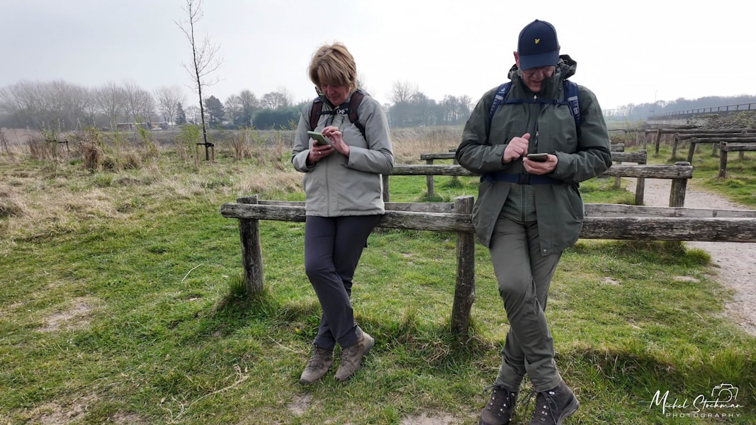 Two people looking at their phones outdoors