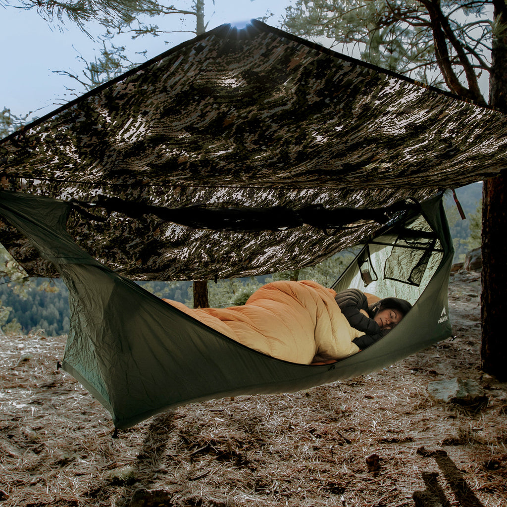Camper sleeping on their side in a Haven Tent XL, lying flat in a sleeping bag under the rainfly